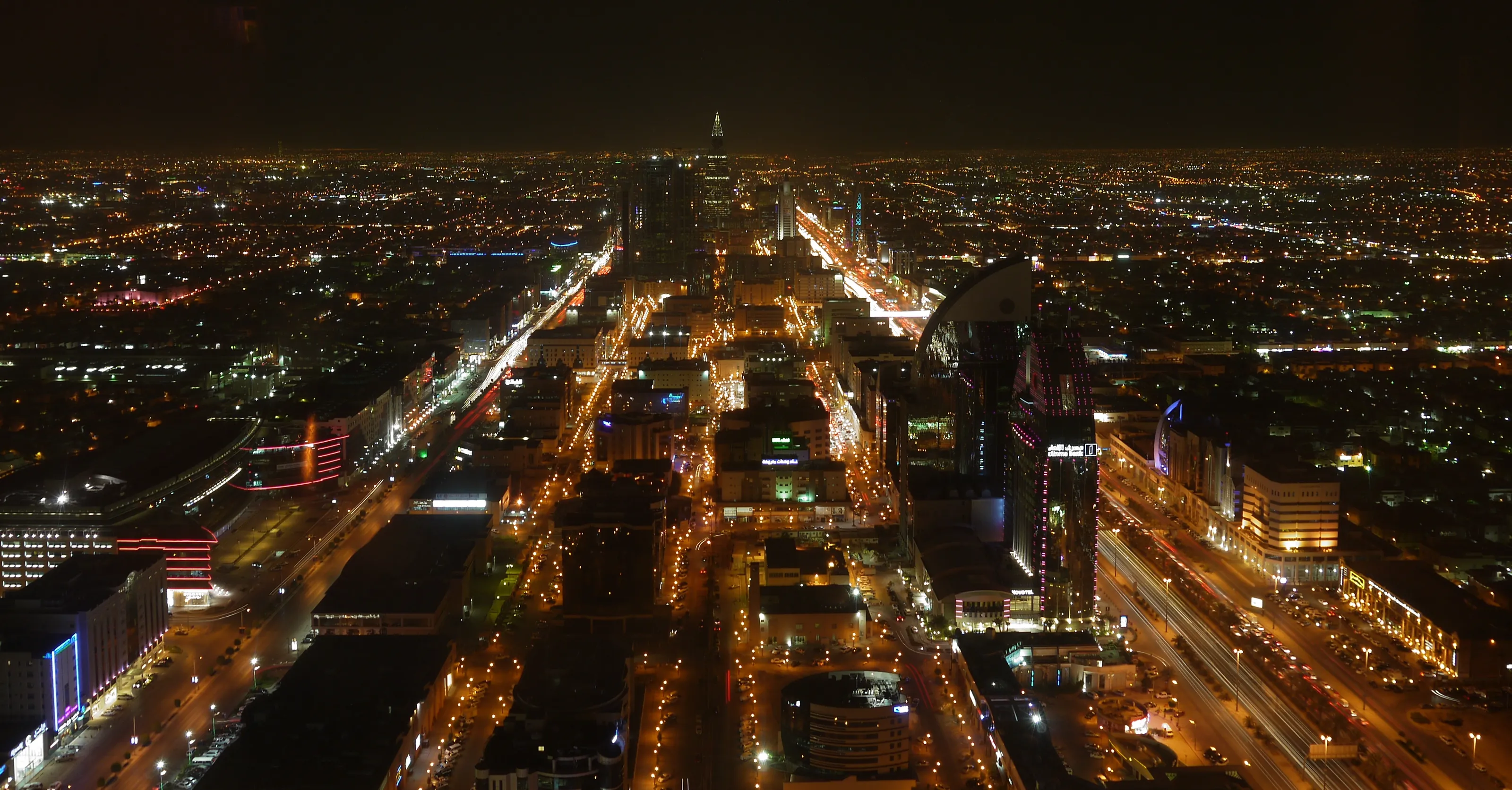 Riyadh at night from above, its main avenues lit end to end.