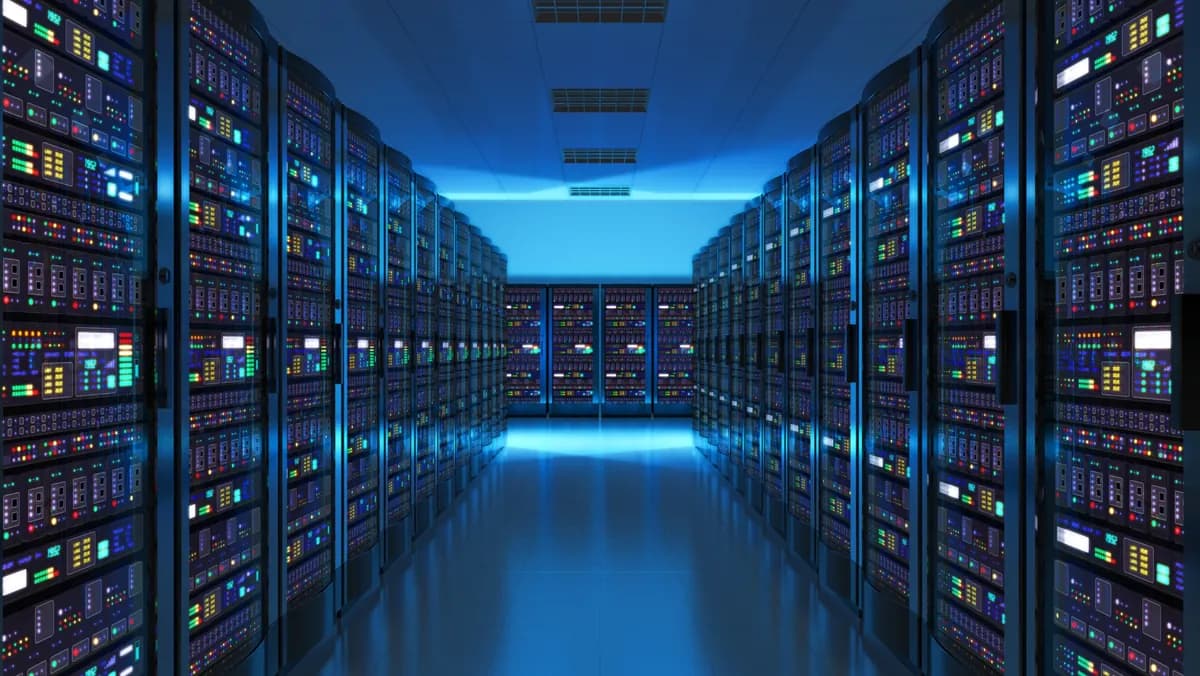 A data center aisle between rows of lit server racks.